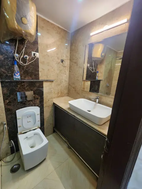 Modern attached bathroom with vessel basin, vanity unit and wall-hung toilet