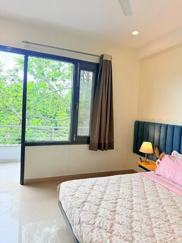 Bedroom with upholstered headboard and large window overlooking greenery